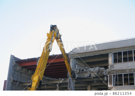 老朽化した公共建造物の解体作業をする重機 86211354