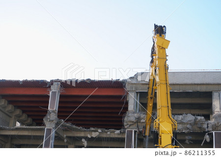 老朽化した公共建造物の解体作業をする重機 86211355