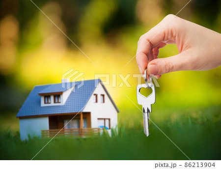 hand holding key against house background 86213904