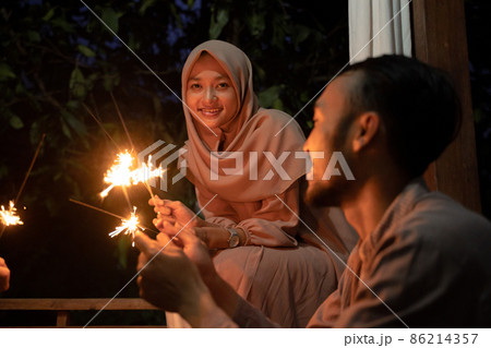 A veiled woman lights fireworks during the celebration A veiled woman lights fireworks during the celebration 86214357