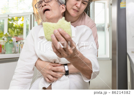 Senior woman with bread stuck in her throat,suffocating due to food clogging the trachea,obstruction of the airway,caregiver doing the heimlich maneuver,helping elderly,choking first aid,life support 86214382