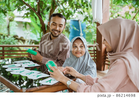 Father, mother and daughter making paper decorations preparing to decorate 86214698