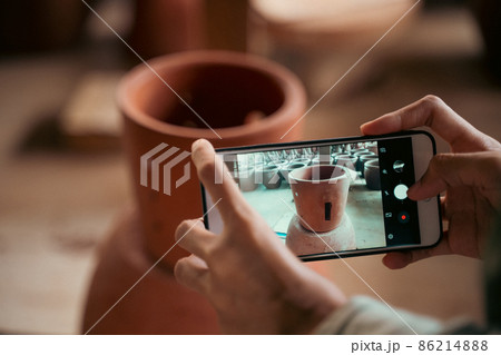hands holding smartphone used to photograph clay crafts hands holding smartphone used to photograph clay crafts 86214888