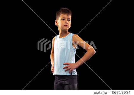 Cropped portrait of little boy, running athlete posing in uniform isolated over black studio background Cropped portrait of little boy, running athlete posing in uniform isolated over black studio background 86215954