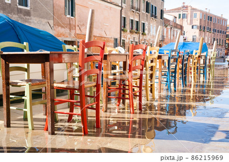 Colorful chairs in a row along Venetian canal 86215969