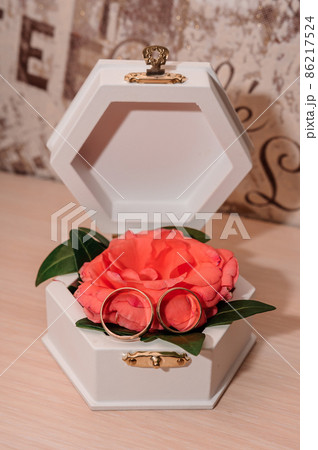 Wedding gold rings on an orange rose in a white box Wedding gold rings on an orange rose in a white box 86217524
