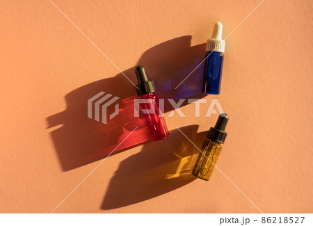 Transparent glass dropper bottles with yellow, green, red and blue liquid inside on beige background in the sunlight. Pipette with fluid hyaluronic acid, serum, retinol. Cosmetics, healthcare, beauty Transparent glass dropper bottles with yellow, green, red and blue liquid inside on beige background in the sunlight. Pipette with fluid hyaluronic acid, serum, retinol. Cosmetics, healthcare, beauty 86218527
