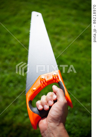 hand saw against green grass background 86218970