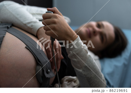 Close Up Pregnant Woman On Hospital Couch During Medical Control Cardiotocography. Visit Gynecologist Doctor At Clinic For Pregnancy Consultant. Examine Expectant Belly Baby Mother Healthcare Check Up Close Up Pregnant Woman On Hospital Couch During Medical Control Cardiotocography. Visit Gynecologist Doctor At Clinic For Pregnancy Consultant. Examine Expectant Belly Baby Mother Healthcare Check Up 86219691