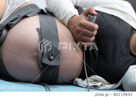 Close Up Pregnant Woman On Hospital Couch During Medical Control Cardiotocography. Visit Gynecologist Doctor At Clinic For Pregnancy Consultant. Examine Expectant Belly Baby Mother Healthcare Check Up Close Up Pregnant Woman On Hospital Couch During Medical Control Cardiotocography. Visit Gynecologist Doctor At Clinic For Pregnancy Consultant. Examine Expectant Belly Baby Mother Healthcare Check Up 86219692