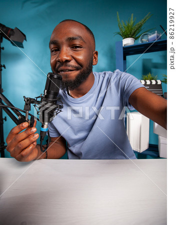 Portrait of smiling social media content creator taking wide angle selfie in online radio studio 86219927