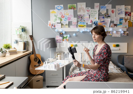Cute teenage girl with pill container and smartphone making video or livestream 86219941
