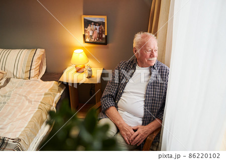 Serene and relaxed senior man sitting in armchair by window Serene and relaxed senior man sitting in armchair by window 86220102