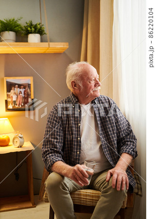Aged restful man in casualwear sitting by window Aged restful man in casualwear sitting by window 86220104