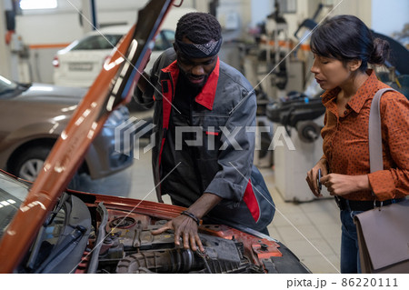 Young African repairman consulting Hispanic female client 86220111