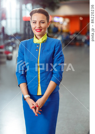 Cheerful woman stewardess standing in airport terminal Cheerful woman stewardess standing in airport terminal 86220236