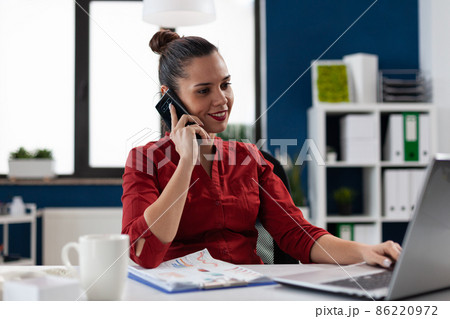 Smiling entrepreneur in red shirt talking on smartphone. Smiling entrepreneur in red shirt talking on smartphone. 86220972