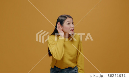 Portrait of woman eavesdropping discussion in studio Portrait of woman eavesdropping discussion in studio 86221031