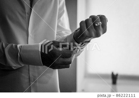 The man fastens the cufflink on the sleeve of his shirt. The groom fastens a button on the sleeve of his shirt The man fastens the cufflink on the sleeve of his shirt. The groom fastens a button on the sleeve of his shirt 86222111