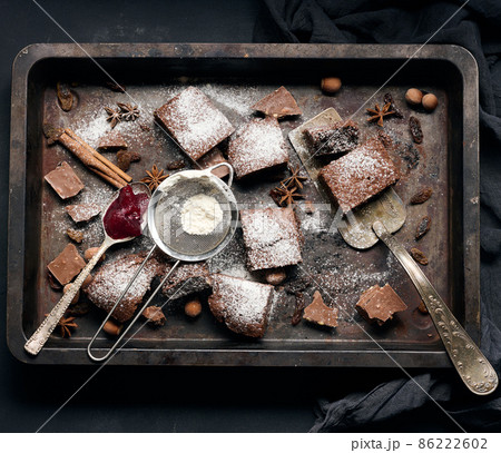 baked square pieces of chocolate brownie sprinkled with powdered sugar on the table baked square pieces of chocolate brownie sprinkled with powdered sugar on the table 86222602