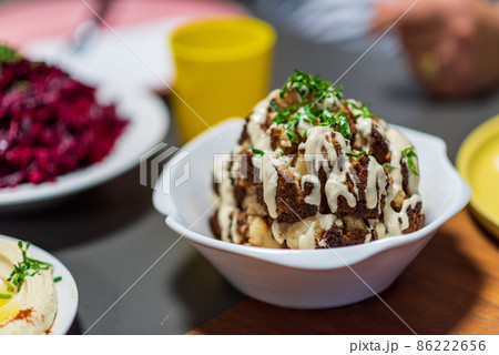 One whole head of roasted cauliflower with roasting ingredients and tahini sauce. Middle Eastern Health Diet. Mediterranean and Balkan food. 86222656