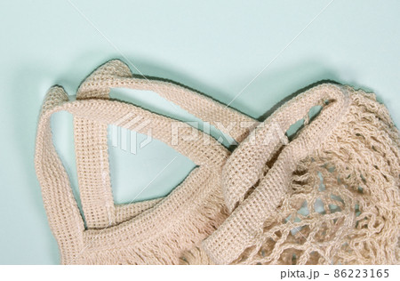 Empty mesh bag on a blue background, top view. Space for text, eco-friendly shopping bag Empty mesh bag on a blue background, top view. Space for text, eco-friendly shopping bag 86223165