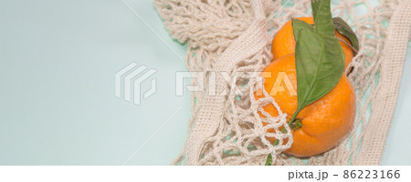 Blue banner background with tangerines in a string bag. Healthy lifestyle, top view, zero waste 86223166