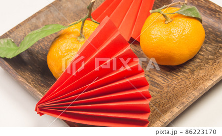 Chinese New Year, composition with tangerines, funny origami made of red paper on a dark wooden plate on a white background Chinese New Year, composition with tangerines, funny origami made of red paper on a dark wooden plate on a white background 86223170