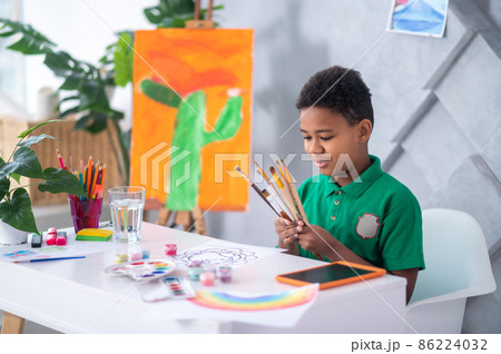 Boy looking at brushes sitting at table 86224032