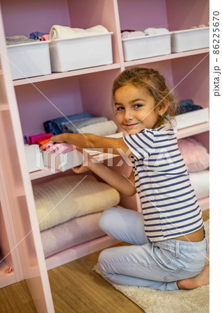 Top view little girl neatly folded clothes into case box for comfortable vertical storage on shelves 86225670