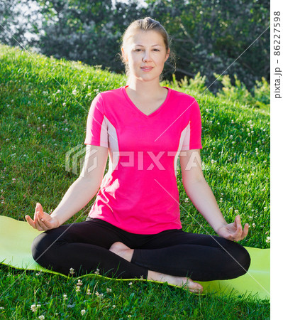 Fitness woman in pink T-shirt is sitting and meditating 86227598