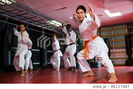 Woman in kimono standing in fight stance in gym Woman in kimono standing in fight stance in gym 86227887