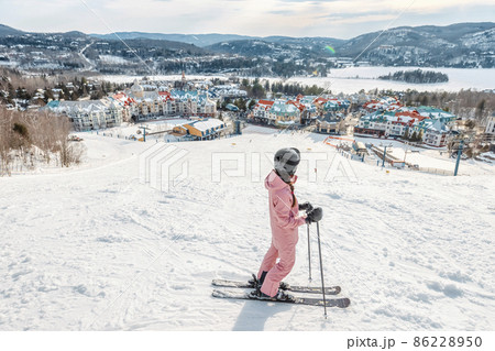 Skiing woman. Alpine ski - skier looking mountain village ski resort view starting skiing downhill on snow covered ski trail slope in winter. Mont Tremblant, Quebec, Canada Skiing woman. Alpine ski - skier looking mountain village ski resort view starting skiing downhill on snow covered ski trail slope in winter. Mont Tremblant, Quebec, Canada 86228950