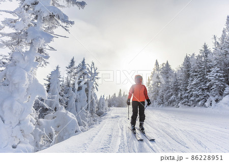 Winter outdoor active lifestyle concept. Girl holding snowball on snowy day with snowman in background on frozen lake at beautiful winter sunset 86228951