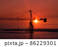 silhouette of tower crane with the sun behind it during the orange sunset 86229301