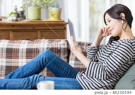 タブレット端末の画面を見ている普段着の女性 86230594