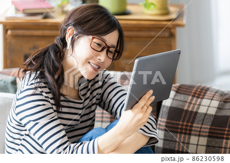 タブレット端末の画面を見ている普段着の女性 86230598