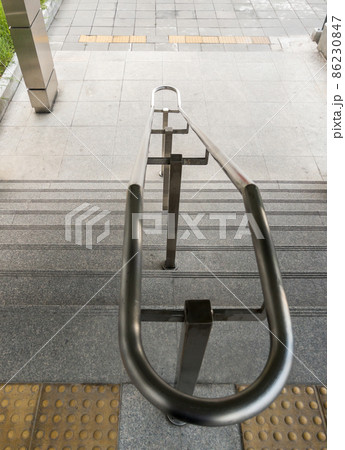 The stainless steel handrail on the staircase near the entrance of the urban railway station. 86230847
