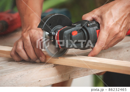 Close up of a carpenter using a circular saw to cut a wood 86232465