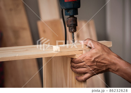 Close-up hands of male artisan drilling lumber in his shop. Concept wood shop of technology and equipment.. 86232628