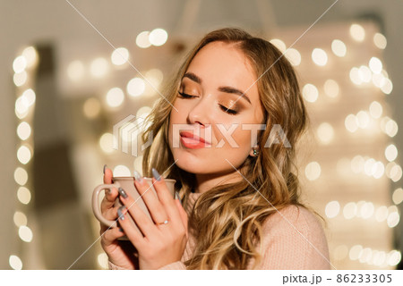 Beautiful young woman celebrating christmas at home, having fun while opening presents 86233305