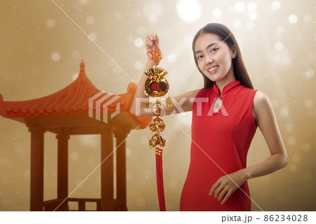 Asian Chinese woman in a cheongsam dress holding Chinese ornament 86234028