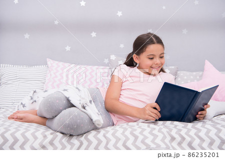 Girl child lay bed read book. Kid prepare to go to bed. Girl child lay bed read book. Kid prepare to go to bed. 86235201