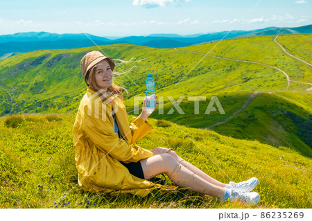 Hiker traveler female holding bottle with fresh water outdoors on the top of the mountain. Drinking water and health Hiker traveler female holding bottle with fresh water outdoors on the top of the mountain. Drinking water and health 86235269