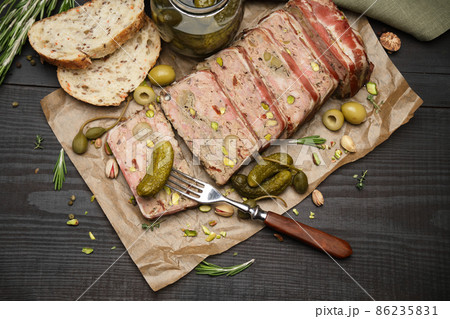 Sliced Traditional French terrine covered with bacon on dark wooden background 86235831