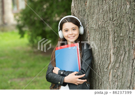 Girl listening audio carry textbooks relaxing park background, sound in her head concept Girl listening audio carry textbooks relaxing park background, sound in her head concept 86237399