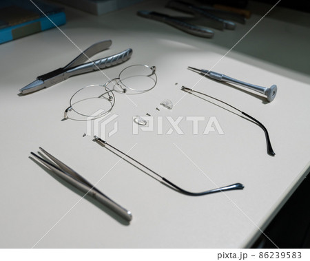 Disassembled glasses frame and tools. Optics work table. 86239583