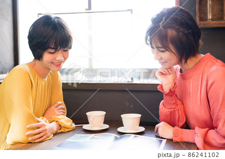 カフェでパンフレットを見て旅行プランを練る二人の女性　 撮影協力「洋菓子店　sentiment」 86241102