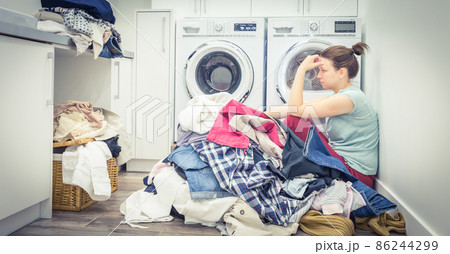 Sad tired Woman in laundry room, blue tone 86244299