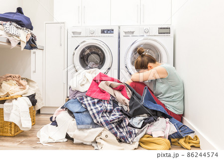 Sad woman sitting in a laundry room Sad woman sitting in a laundry room 86244574